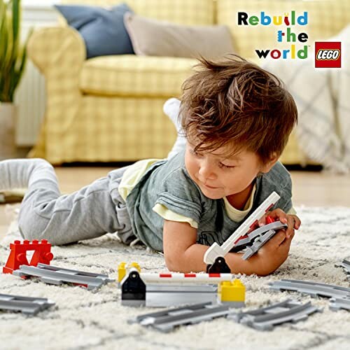 Kind speelt met LEGO treinset op de vloer.