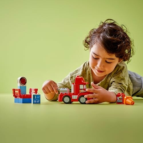 Kind speelt met speelgoedbrandweerwagen op groene achtergrond.
