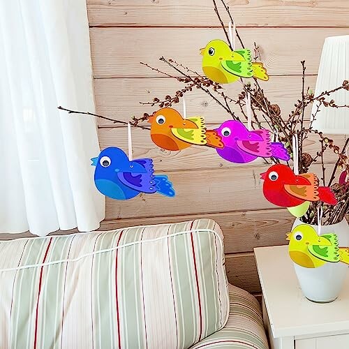 Kleurrijke papieren vogels hangen aan een tak.